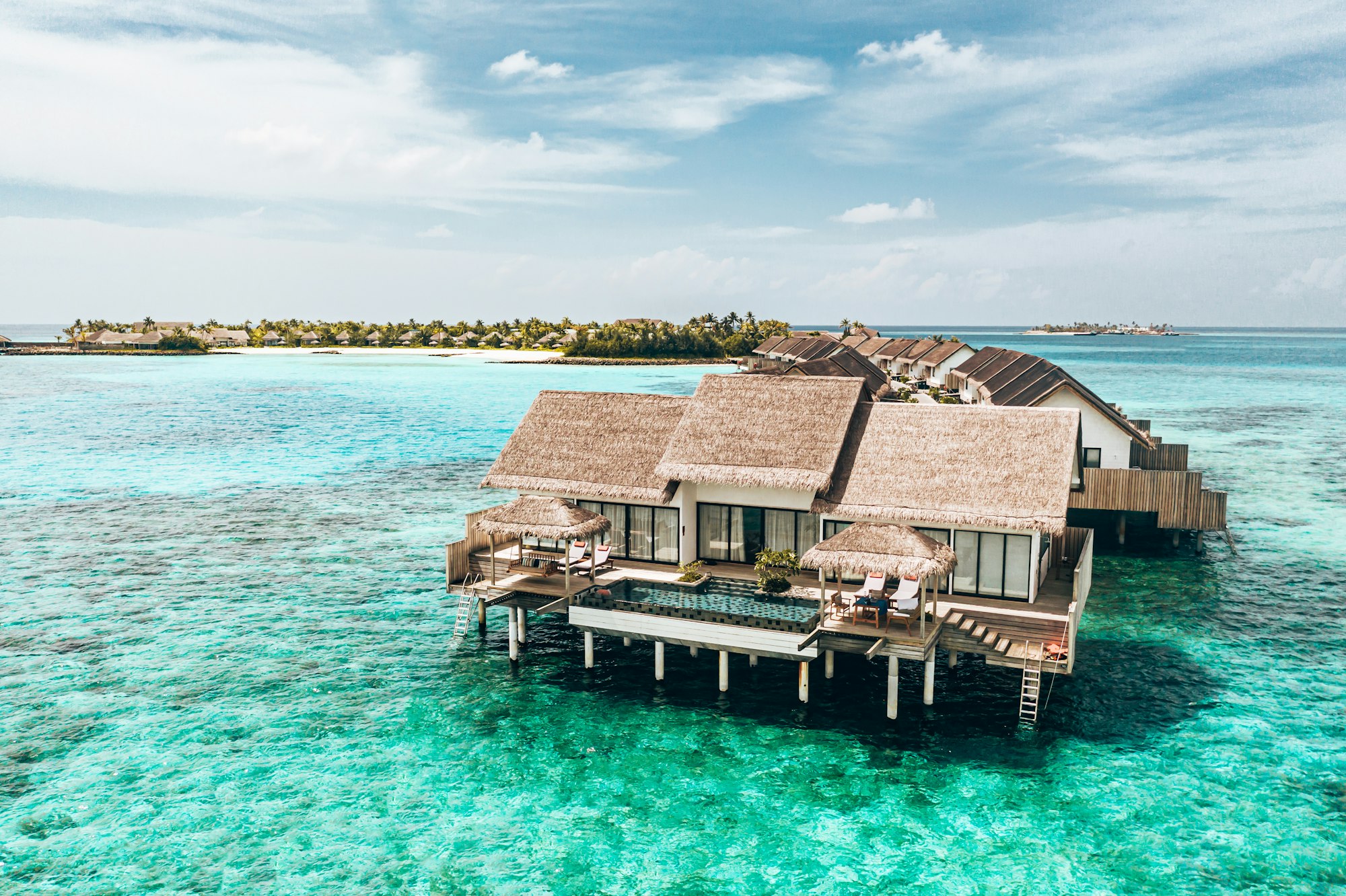 Overwater villas above turquoise water at a luxury island resort